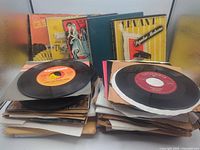 Two stacks of loose 45s in sleeves and several boxed sets behind