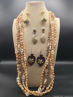 Full lot on display bust showing four shell necklaces and three pairs of earrings