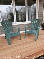 Two green plastic Adirondack chairs on wooden deck