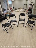Set of four black folding chairs arranged in a row
