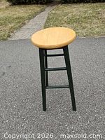 Full view of wooden stool standing upright on pavement