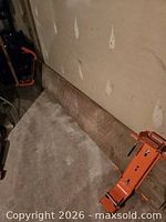 Wood plank along wall with attached orange bracket