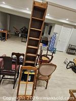 Front view of tall wooden CD shelf with smaller mirror frame leaning nearby