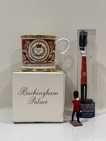 Mug on box beside toothbrush in tube and metal guard figure