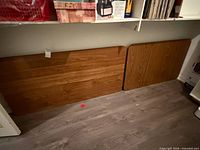 Two faux wood folding table tops leaning against wall