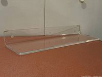 Single acrylic shelf showing top and mounting flange