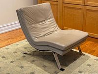 Front angled view of beige leather lounge chair on chrome base