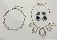 Overview of both necklaces and pair of earrings