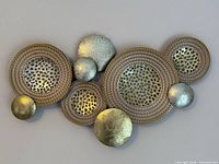 Full view of metal wall sculpture showing all overlapping discs and coloration