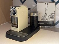 Front angled view of cream Nespresso CitiZ & Milk machine with Aeroccino and descaling kit