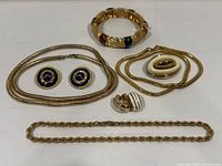 All seven jewelry pieces laid out: two necklaces, three bracelets, two pairs earrings