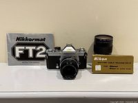 Camera body with attached 50mm lens, manual, boxed cable, additional zoom lens