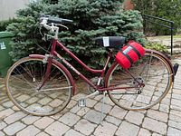 Full left side view of raspberry red Schwinn Worldtour bicycle with pannier bag