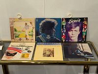 Six vinyl album covers laid out on glass table