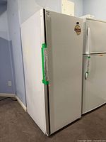 Front and right side view of white Woods upright freezer
