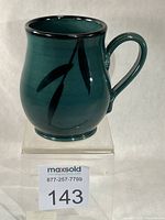 Front view showing emerald green glaze, leaf motif and handle
