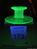 Candlestick glowing bright green under UV light, front view