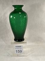 Full frontal view of emerald green crackle glass vase on clear stand