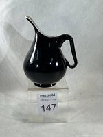 Front view of black and white cased glass pitcher showing overall form and applied handle