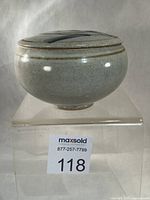Front view of lidded stoneware jar on stand