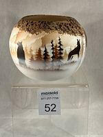 Front view of rounded pottery vase showing wolf and bear silhouettes with forest scene