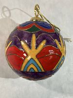 Oblique view of ornament showing purple, red, yellow, blue design
