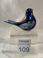 Side view of iridescent glass bird figurine on clear stand