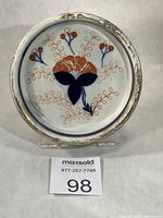 Front view of round Old Imari dish with floral motif and worn gilt rim