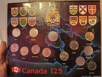 Front of Canada 125 map board showing coin recesses, some filled