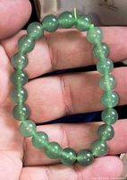 Full view of elastic bracelet with green beads in hand