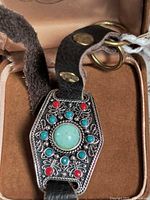 Bracelet in case showing front decorative plaque and leather strap