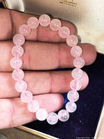 Rose quartz bracelet held in hand showing bead size and elastic cord