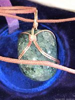 Front view of quartz pendant wrapped in copper wire on brown cord