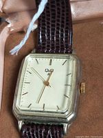 Front view of Q&Q rectangular watch face on burgundy leather strap