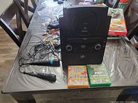 Entire lot showing karaoke machine, two microphones, RCA cables, two Party Tyme CD packs