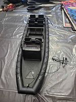 Full view of black plastic boat hull with rudder and propeller assembly