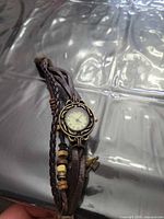 Watch showing case, dial, braided band, beads, arrow charm