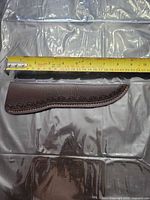 Full view of brown leather sheath beside measuring tape showing ~9 in length