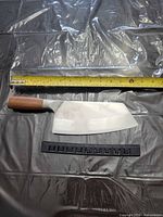 Knife and guard laid beside tape measure indicating blade length, showing Damascus pattern and wooden handle