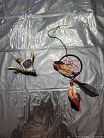 Dreamcatcher with feathers and beads alongside shed antler decor piece on plastic sheet background