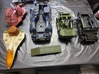 Overview of five GI Joe vehicles and loose bridge part on table