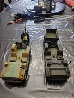 Overview of two military toy vehicles and a towed artillery gun showing colors and wear
