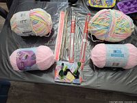 Overview of all yarn skeins, knitting needles, crochet hooks and embroidery floss on table