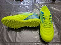 Top and side view of both turf shoes showing color, studded sole and lace-up design