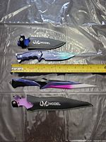 Two UM Model fixed blade knives with sheaths and measuring tape