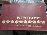 Closed burgundy Poleconomy box top with maple leaves and bilingual title
