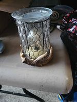 Glass and mesh candle holder with faux antler base and candle inside