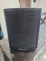 Front view of black Showbox speaker showing curved slat grill and logo