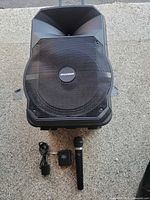 Front view of Sylvania portable PA speaker with microphone and power adapter