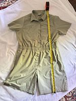 Full view of Columbia short sleeve shorts jumpsuit laid flat with tape for scale